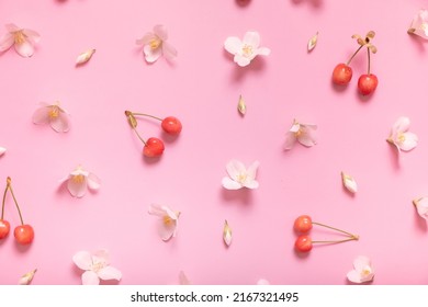 Pattern with jasmine flowers and sweet cherry on pastel pink background, lay flat, the top view.