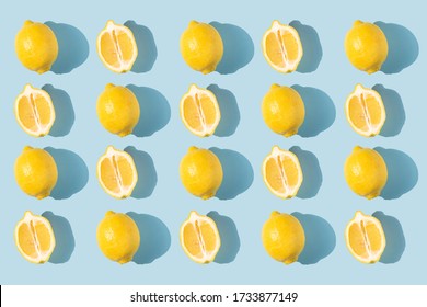 Pattern of lemons with shadow on a blue background. complementary colors. Fresh bright fruits, vitamins. Healthy eating concept. Some lemons are sliced. Halves of lemons.