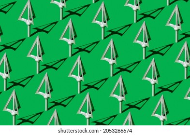 Pattern made of broadhead with sunshine shadow, against green background. Minimal Christmas tree idea.