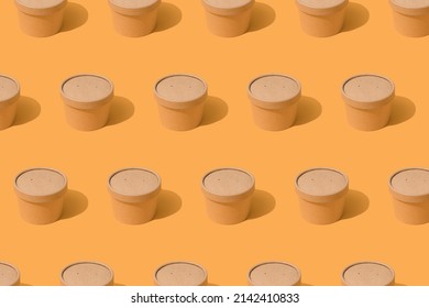 Pattern made with brown disposable kraft paper street food container or cup with paper cap on orange background with copy space, mockup. Sustainable food packaging concept