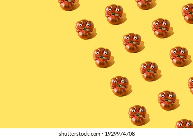 Pattern made of fresh tomato primora with googly eyes against yellow background.  Creative food layout with copy space. Funny  vegetable concept.