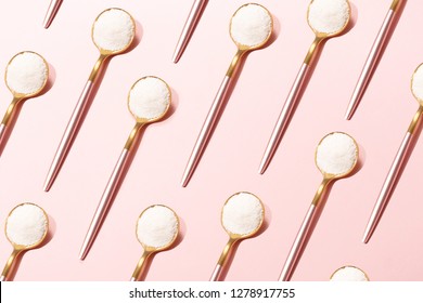 Pattern made with spoons with collagen or protein powder on pale pink background. Natural beauty and health supplement for skin, bones, joints and gut. Plant or fish based. Flatlay, top view.