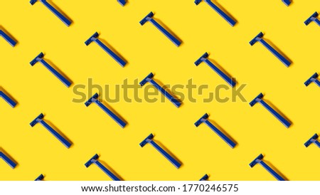 pattern of many copy pasted plastic blue shaver razors on yellow background . top side view. minimal pop up style. Banner, desktop, print, wallpaper. 16:9