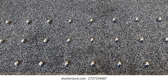 A pattern of metal studs, installed as a form of hostile architecture.They are installed on ledges or flat surfaces to deter people from sitting, lying down, or seeking shelter in public spaces.