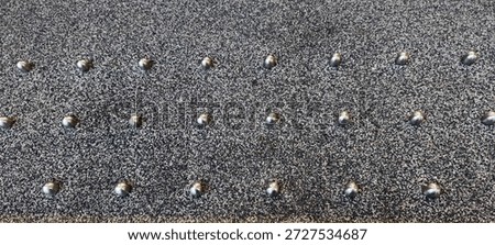 A pattern of metal studs, installed as a form of hostile architecture.They are installed on ledges or flat surfaces to deter people from sitting, lying down, or seeking shelter in public spaces.
