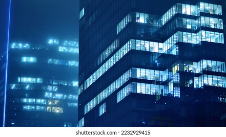 Pattern of office buildings windows illuminated at night. Glass architecture ,corporate building at night - business concept. Blue graphic filter. - Shutterstock ID 2232929415