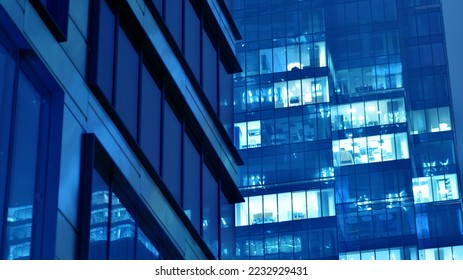 Pattern of office buildings windows illuminated at night. Glass architecture ,corporate building at night - business concept. Blue graphic filter. - Shutterstock ID 2232929431