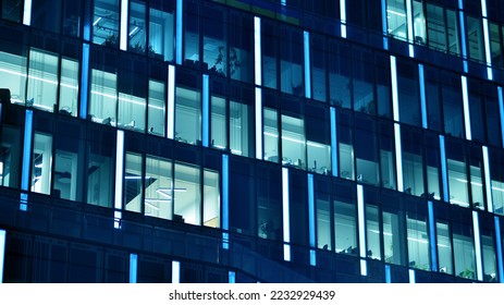 Pattern of office buildings windows illuminated at night. Glass architecture ,corporate building at night - business concept. Blue graphic filter. - Shutterstock ID 2232929439