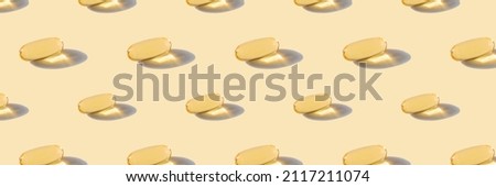 A pattern of omega capsules on a beige background.