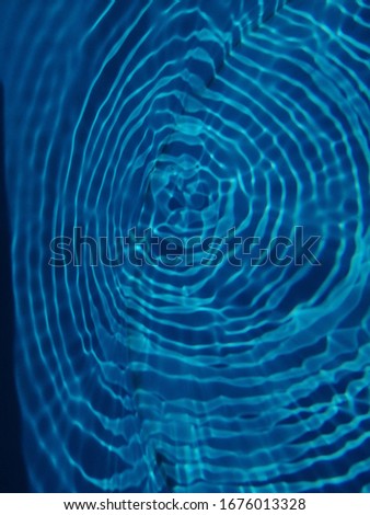 The​ pattern of​ surface​ blue​ water​ in​ the​ swimming​ pool reflected​ with​ sunlight​ for​ background. Abstract​ of​ surface​ blue​ water​ for​ background​