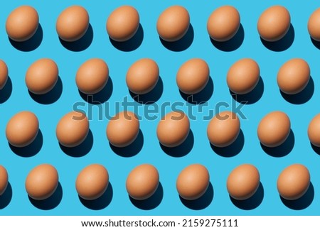 Pattern of raw brown chicken eggs isolated on blue background. Happy Easter day. Close-up, top view.