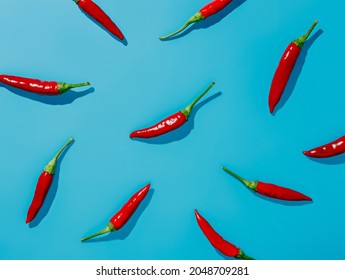 Pattern With Red Hot Chili Peppers On Vibrant Blue Background. Creative Food Concept. Minimal Dish, Spicy Spices For Cooking, Cayenne Pepper Idea. Fashion Minimal Art. Flat Lay, Overhead.