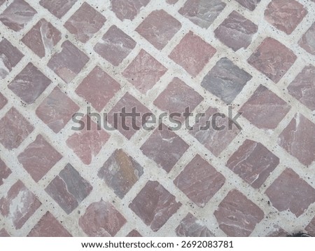 Pattern of red regular sandstone blocks as paving for the footpath, Alsace, France