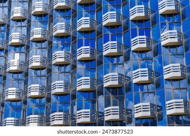 Pattern of repeating steel balconies adorning the facade of a contemporary glass building, showcasing modern architectural design. - Powered by Shutterstock
