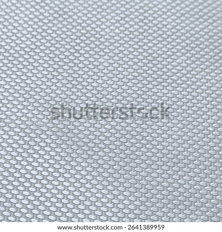 a pattern of small dots arranged tightly and evenly. The pattern resembles a fine net texture with small round hexagonal shapes. The dominant color is light gray.
