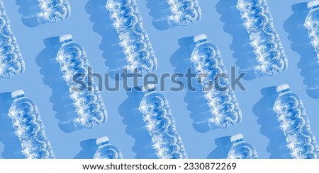 Pattern small plastic bottles with clean drinking water at sunlight, hard shadow on blue background, banner. Full closed bottle water. Pollution, plastic garbage, non-biodegradable packaging waste