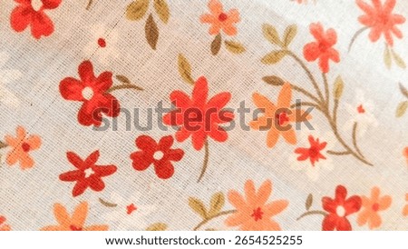 A pattern of small red, orange and white flowers on cotton or linen fabric.