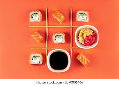 Pattern of sushi rolls Philadelphia with salmon on an orange background. Sushi is spread out like in a game of tic-tac-toe