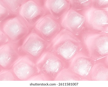 Pattern and texture of naturally clear ice cubes isolated on a pink background. Top view of ice cubes with scattered water droplets on a pink backdrop. Ice cube concept for cold drinks.