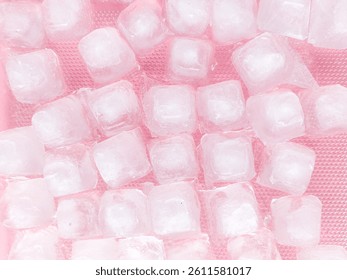 Pattern and texture of naturally clear ice cubes isolated on a pink background. Top view of ice cubes with scattered water droplets on a pink backdrop. Ice cube concept for cold drinks.