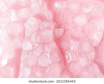 Pattern and texture of naturally clear ice cubes isolated on a pink background. Top view of ice cubes with scattered water droplets on a pink backdrop. Ice cube concept for cold drinks.