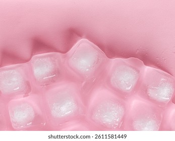 Pattern and texture of naturally clear ice cubes isolated on a pink background. Top view of ice cubes with scattered water droplets on a pink backdrop. Ice cube concept for cold drinks.