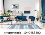 Patterned carpet in pink and blue living room interior with sofa against white wall with painting