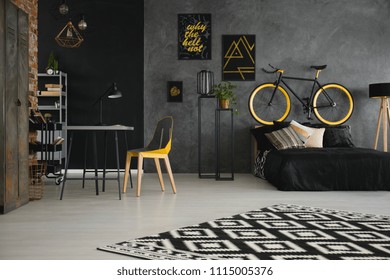 Patterned Carpet In Teenager's Room Interior With Yellow Chair At Desk And Bike Above Bed. Real Photo