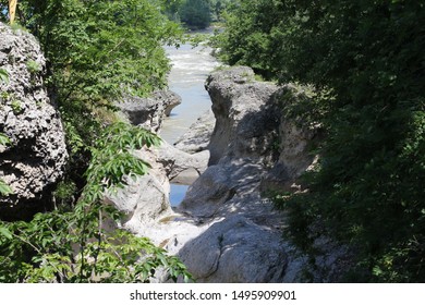 patterned cliffs on a background of a mountain river surrounded by green deciduous trees