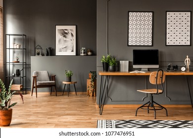 Patterned posters above desk with computer monitor in grey home office interior with plants - Shutterstock ID 1077476951
