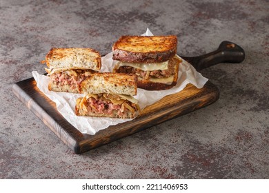 Patty Melt Sandwich Has A Burger Patty Covered With Melted Swiss Cheese, Caramelized Onions, And Griddled Slices Of Rye Bread Closeup On The Wooden Board On The Table. Horizontal
