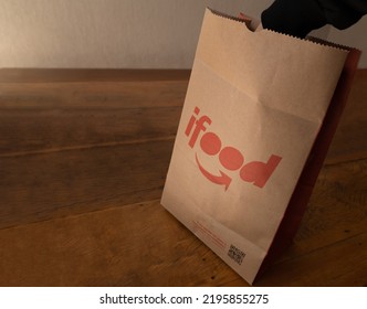 São Paulo, Brazil. August 20, 2022. Hand Open Ifood Delivery Bag On Wooden Table.