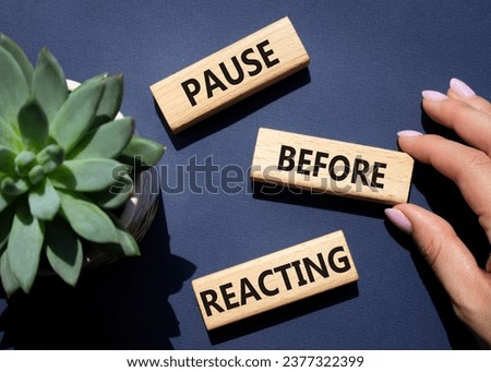 Pause before Reacting symbol. Concept words Pause before Reacting on wooden blocks. Beautiful deep blue background with succulent plant. Businessman hand. Business concept. Copy space.