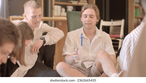 Pause the focus attention session. The guy lecture sitting on floor throws pen up, to give relaxation in independent game reaction. Finding mental balance.
