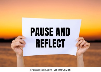Pause and reflect message written on white paper with blurry lake background. Conceptual pause and reflect symbol. Copy space.