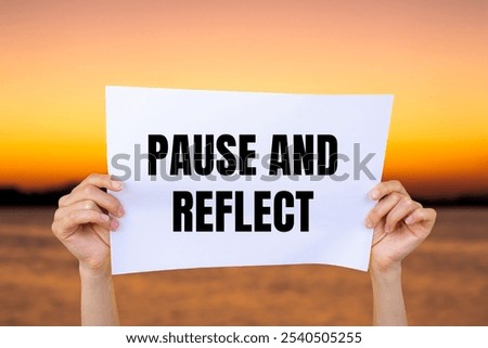 Pause and reflect message written on white paper with blurry lake background. Conceptual pause and reflect symbol. Copy space.