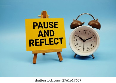 Pause And Reflect text with alarm clock on blue background