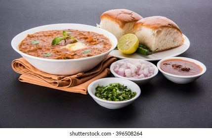 Pav Bhaji is a fast food dish from India, Thick and spicy vegetable curry, fried and served with a soft bread roll/Bun Paav and butter. Served over colourful or wooden background. selective focus