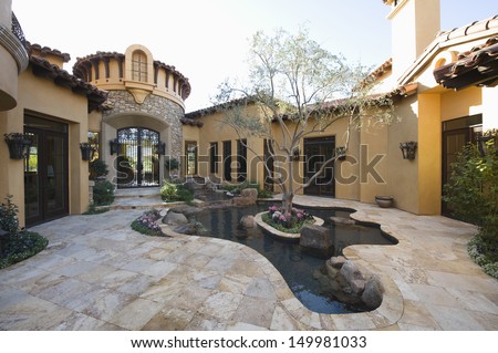 Paved courtyard garden with pond in house against clear sky