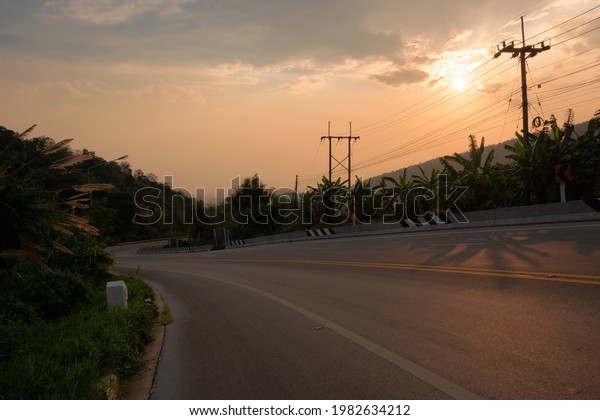 Paved road curve on mountains.Road\
dividing line.The road to the mountain in sunset\
time