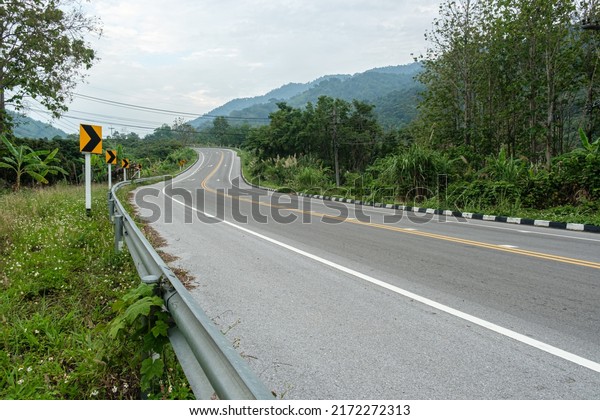 Paved road curve\
on mountains.Road dividing line.The asphalt road on both sides of\
the road is covered with\
grass.