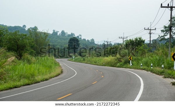 Paved road curve\
on mountains.Road dividing line.The asphalt road on both sides of\
the road is covered with\
grass.