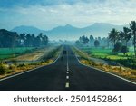 A paved road passing through field rice forest with mountains in the background at Lombok, Indonesia