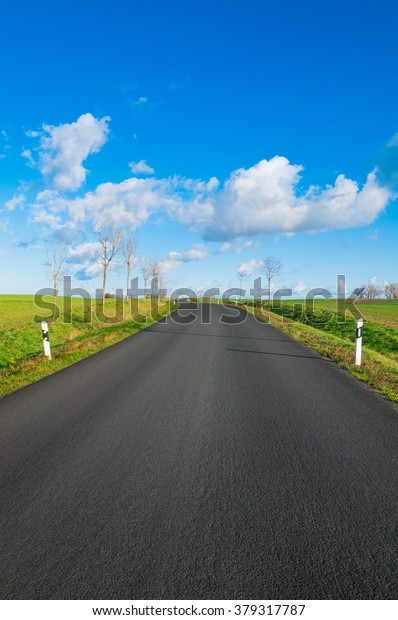 Paved\
road through flat landscape on sunny day in\
winter