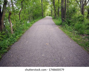 Paved Walking And Cycling Path Running Through The Forest. Well Maintained. Taken In Portland, Michigan Around Mid-May. No People.