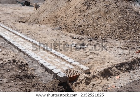 Pavement restoration work, creating a channel for the drainage of rainwater, in stone.