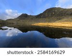 Pavey Ark reflections in Stickle Tarn with dramatic blue sky. Lake District, UK.