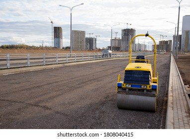 Paving Roller Machine During Road Work. Mini Road Roller At Construction Site For Paving Works. Screeding The Sand For Road Concreting. Asphalt Pavement Is Layered Over Concrete Pavement