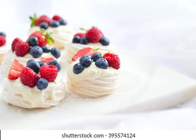 Pavlova berry cake with blueberries, strawberries, raspberries and vanilla ice cream on a marble background