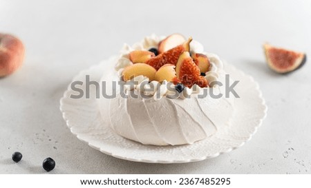 Pavlova cake with peach, figs, blueberries and vanilla cream on a white background. Close up.
